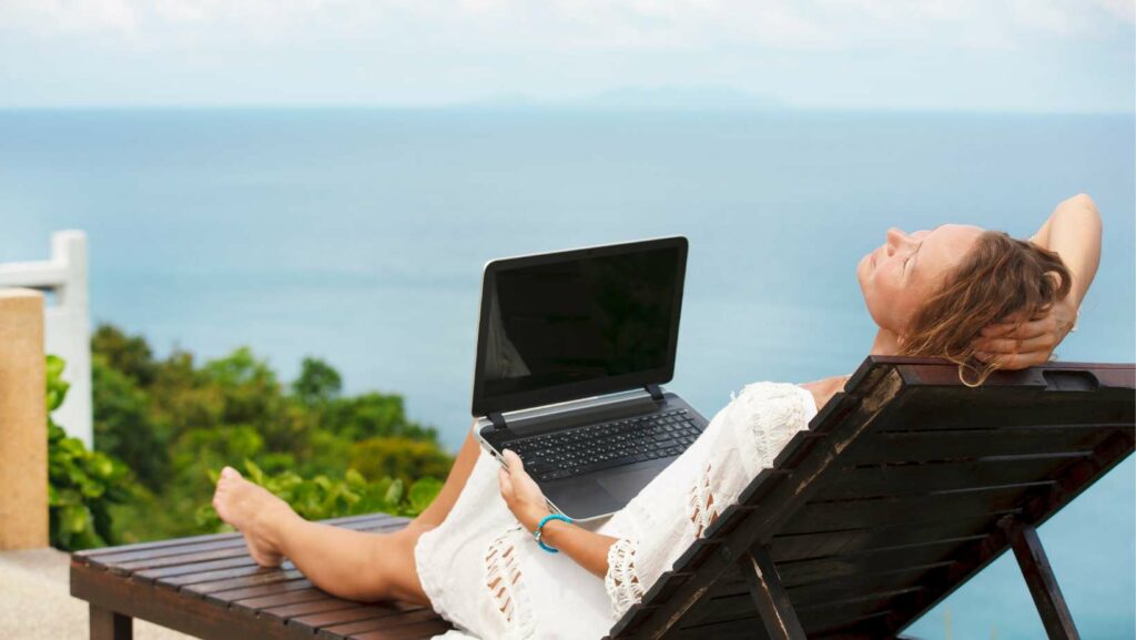zarobić pieniądze w wakacje kobieta z laptopem na plaży
