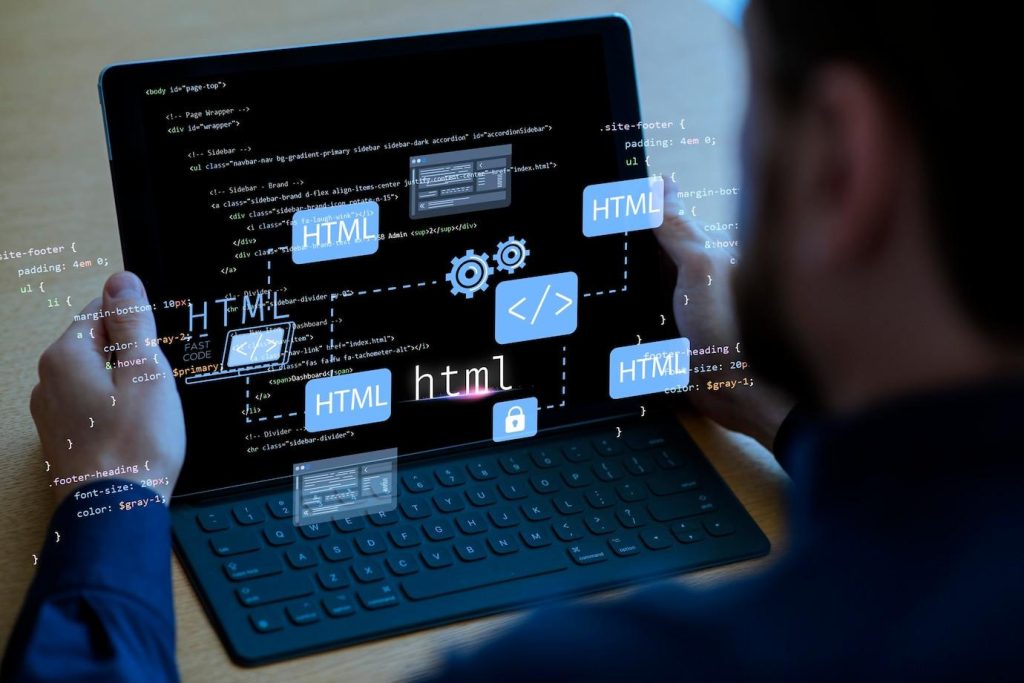 znaczniki HTML, schematy, w tle laptop lub tablet z klawiaturą