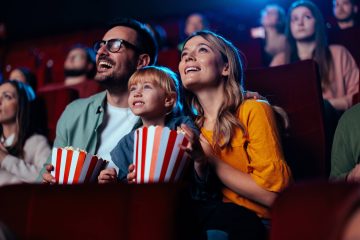 Młoda, radosna para jest z córką w kinie i ogląda ekscytujący film